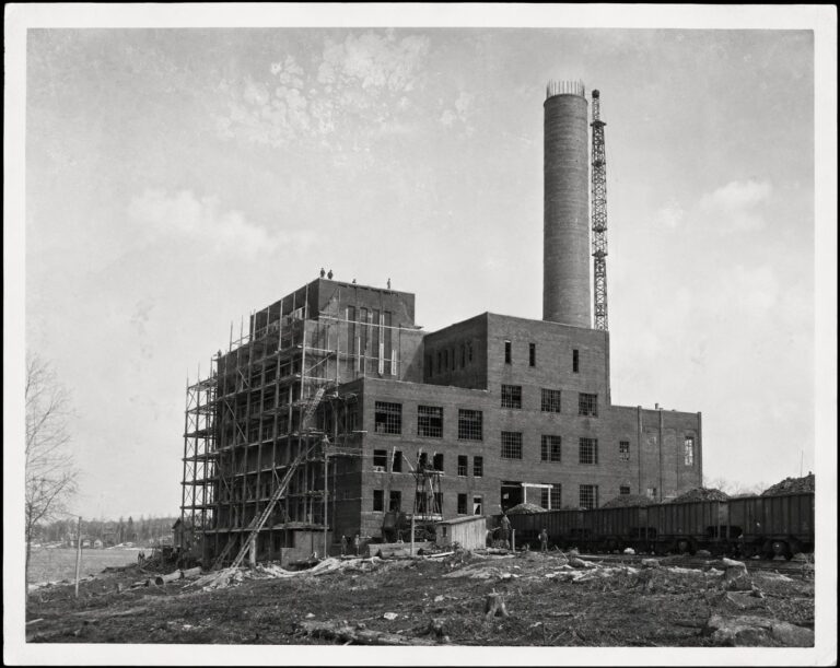 The four-storey brick Power Station under construction with scaffolding and coal cars, circa 1950