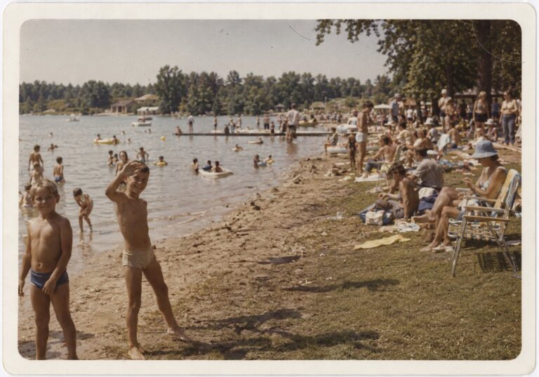 Boys waving at the crowded town beach during Lake Days, circa 1976