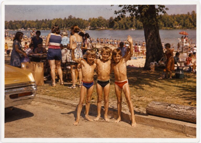 Three boys posing by the picnic tables at the crowded town beach, summer 1976