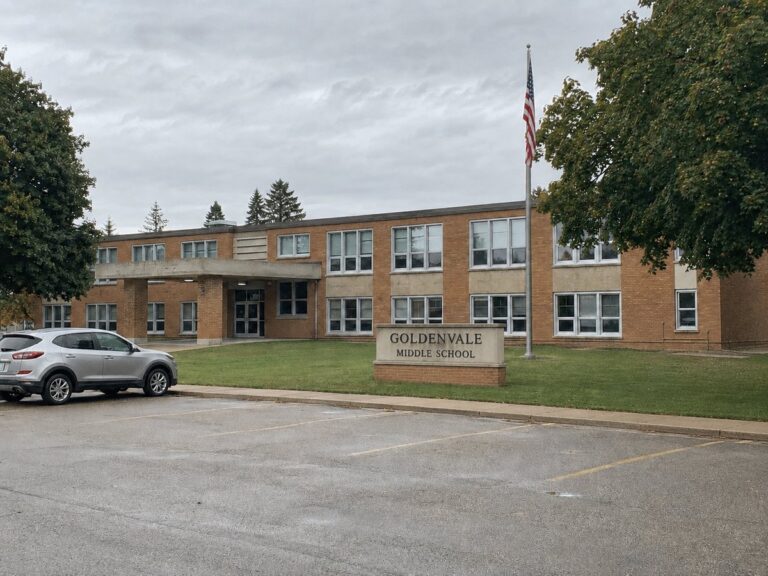 Goldenvale Middle School with its sign and flagpole, seen from the front parking lot